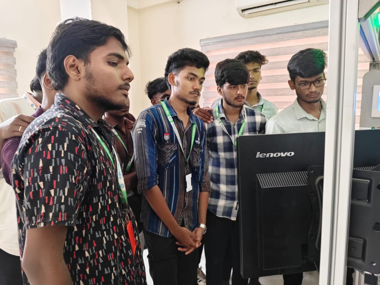 Students gathered around a workstation following a ladder-logic program on screen